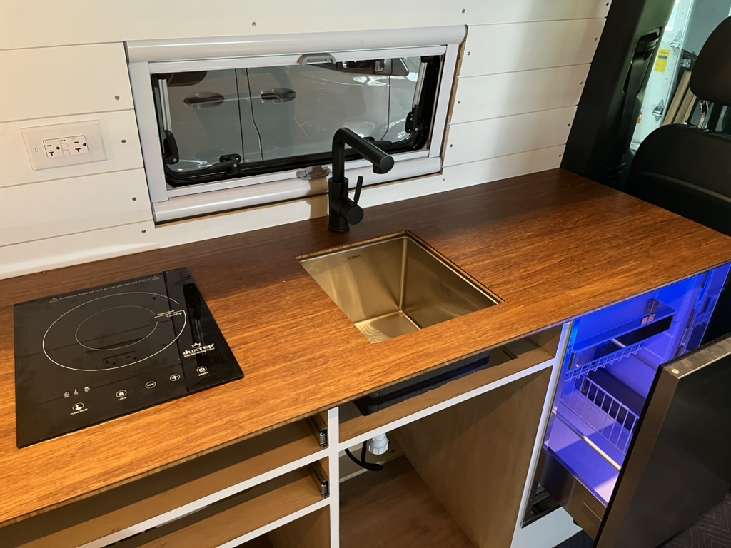 Custom galley with sink, cooktop, drawers, and refrigerator