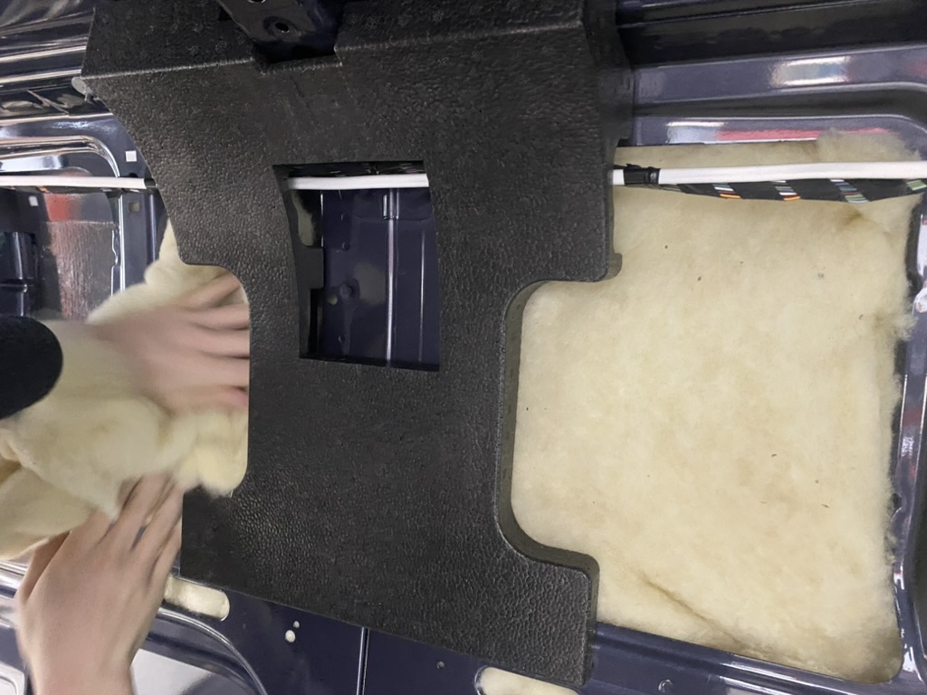 Hands installing natural insulation inside a van wall
