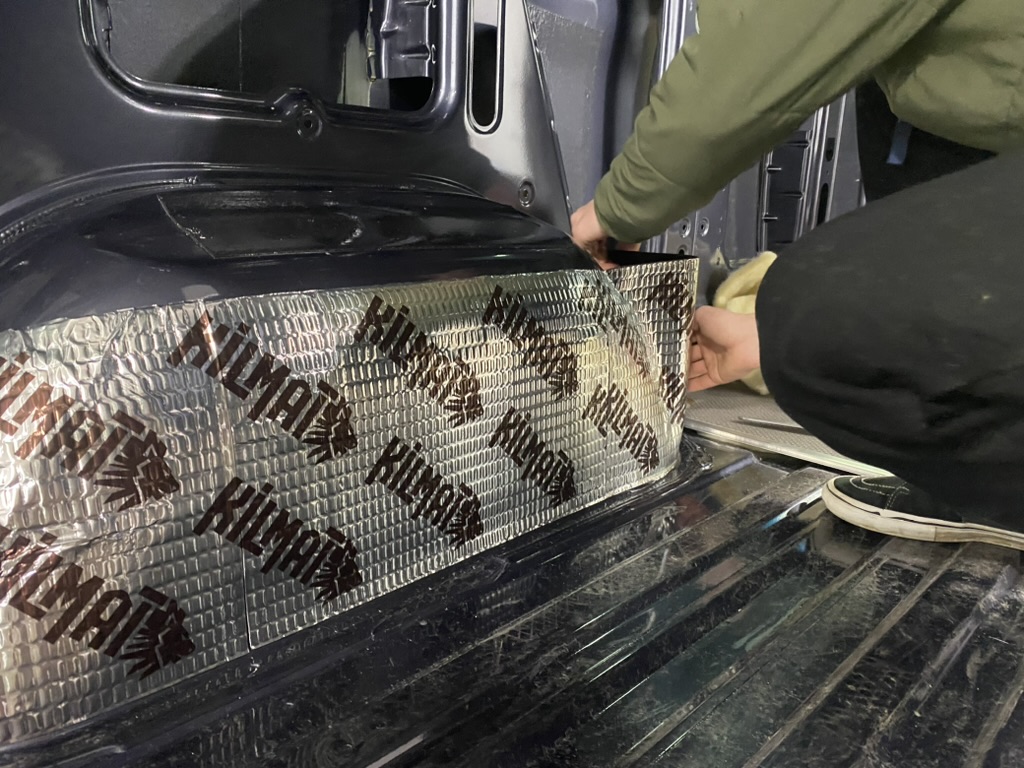 Sound-deadening material being fitted around a van wheel well